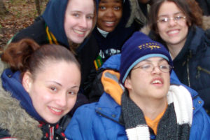 Group of 5 adolescents smiling with winter gear on outside.