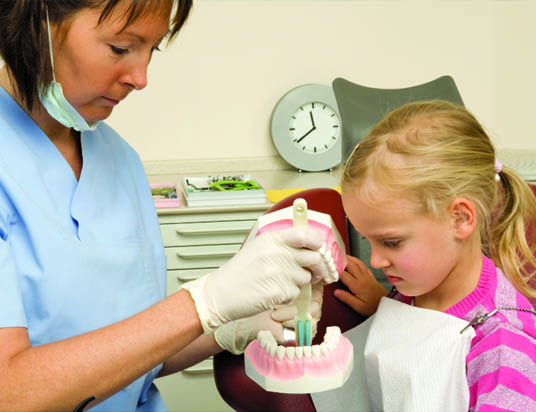 dentist with young girl looking at teeth